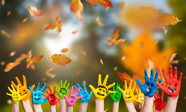 in bunten Farben angemalte Kinderhände vor Herbsthintergrund