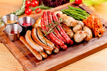 Oktoberfest food menu. Assorted grilled sausages, sauerkraut, green beans on wooden cutting board. Close up