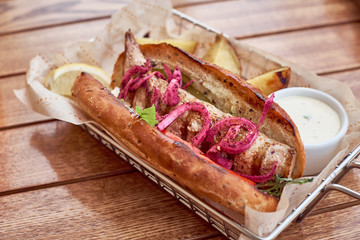 Hot dog fully loaded with assorted toppings on a paddle board, overhead scene