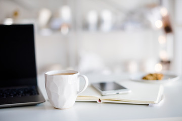 Modern white office, designer handmade cup with coffee, smartpho