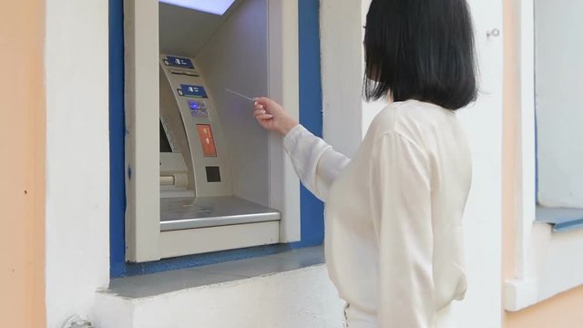 young woman inserting a credit card to ATM, beautiful girl banking, business woman after work in bank, shopping mall