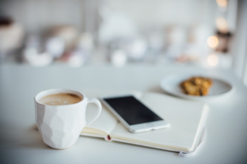 Modern white office, designer handmade cup of coffee, smartphone