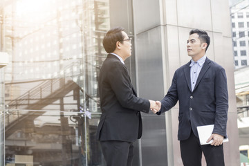 Fototapeta premium Successful negotiating business concept, Businessmen shaking hands after finishing meeting or setting goals and planning way to success in front of building