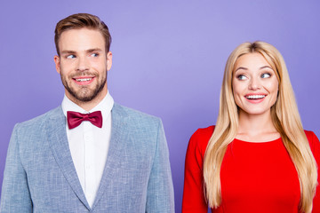 He and she so happy and dreamy! Photo of handsome curious brunet man and blonde lady with straight hair look to each other in classy wear with bowtie isolated on bright purple violet background