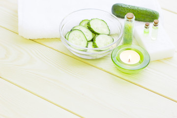 Cucumber home spa and hair care concept. Sliced cucumber, bottles of oil, jar of mask, bathroom towel. White board background