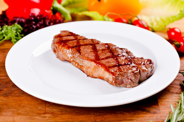 Grilled beef steak on white plate. Close up