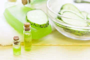 Obraz na płótnie Canvas Cucumber home spa and hair care concept. Sliced cucumber, bottles of oil, soap, jar of mask, bathroom towel. White board background