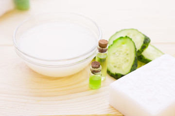 Cucumber home spa and hair care concept. Sliced cucumber, bottles of oil, soap, jar of mask, bathroom towel. White board background
