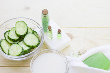 Cucumber home spa and hair care concept. Sliced cucumber, bottles of oil, soap, jar of mask, bathroom towel. White board background
