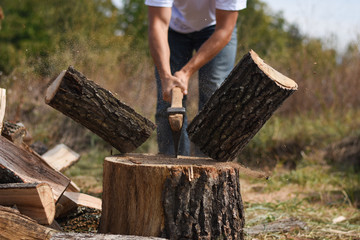 Lumberjack chopping wood for winter, Young man chopping woods with an axe