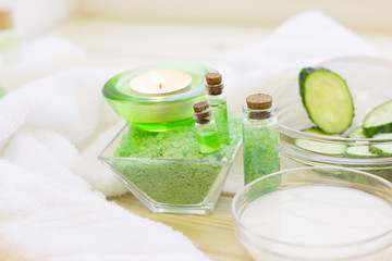 Cucumber home spa and hair care concept. Sliced cucumber, bottles of oil, sea salt, bathroom towel. White board background