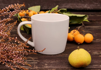 Autumn styled botanical arrangement. Composition of little apples , little pear,and a cup of coffee on wooden table background. Fall decorative concept.