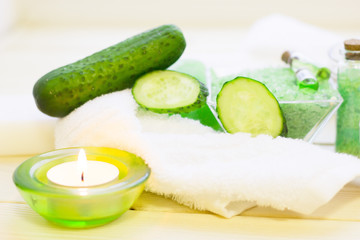 Cucumber home spa and hair care concept. Sliced cucumber, bottles of oil, soap, jar of mask, bathroom towel. White board background