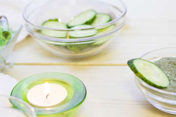 Cucumber home spa and hair care concept. Sliced cucumber, bottles of oil, sea salt, bathroom towel. White board background