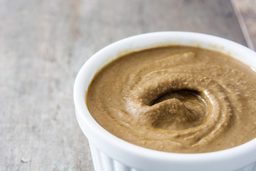 Tahini and sesame seeds on wooden table. Close up