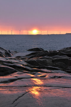 A beautiful combination of a golden sunset, turbines and rocky shore. In Kallo Island, Pori, Finland.