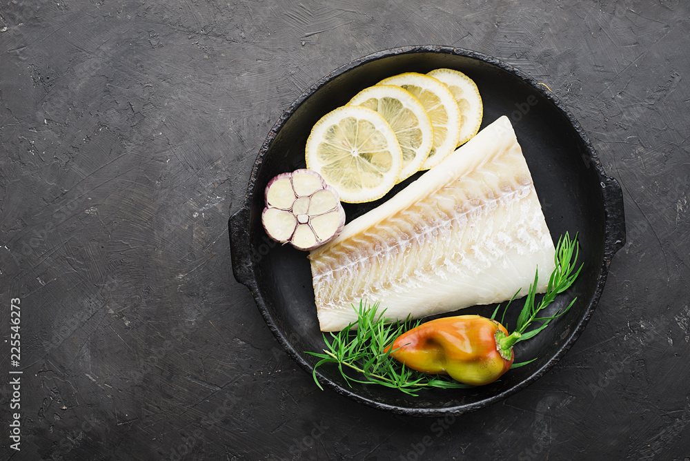 Wall mural a dish of healthy cuisine with seafood: cod is a white sea fish with lemon slices, olives, sea salt 