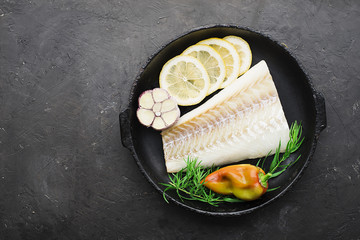 A dish of healthy cuisine with seafood: cod is a white sea fish with lemon slices, olives, sea salt...