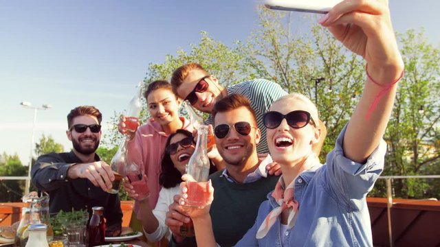 leisure and people concept - happy friends having bbq party on rooftop in summer and taking selfie by smartphone