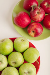 Red and green apples on a plate on a white background.