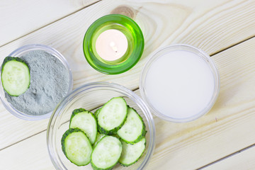 Cucumber home spa and hair care concept. Sliced cucumber, bottles of oil, sea salt, bathroom towel. White board background