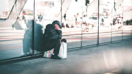 Homeless man sitting on sidewalk