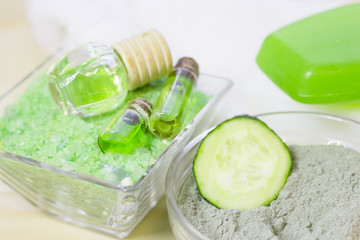 Cucumber home spa and hair care concept. Sliced cucumber, bottles of oil, sea salt, bathroom towel. White board background