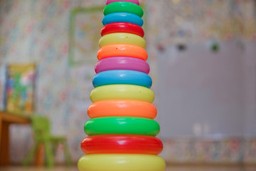 Children's plastic pyramid, composed of colored rings on yellow background