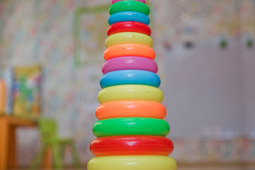 Children's plastic pyramid, composed of colored rings on yellow background