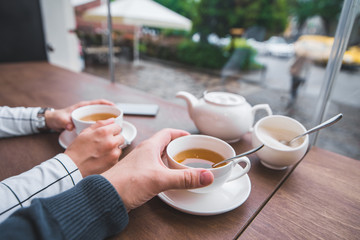 couple sitting in cafe drinking warm up tea in cold autumn day