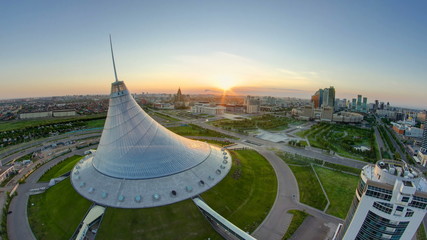 Elevated view with sunrise over the city center with Khan Shatyr and central business district Timelapse, Kazakhstan, Astana - obrazy, fototapety, plakaty