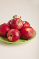Red and green apples on a plate on a white background.