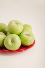 Red and green apples on a plate on a white background.