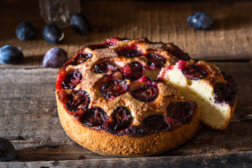 Homemade plum pie on the old wooden background. Still life of food. plum tart. Autumn harvest. Old fashion cuisine. Portion of pie. Plum bakery. Rustic open pie. Winter pie. New York pie.
