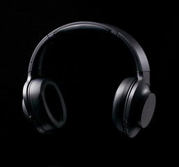 Fototapeta na wymiar Black bluetooth headphones on black background