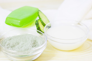 Cucumber home spa and hair care concept. Sliced cucumber, bottles of oil, sea salt, bathroom towel. White board background
