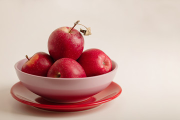 Red and green apples on a plate on a white background.