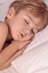 Fototapeta na wymiar handsome european boy sleeps sweetly on the bed. The child is sleeping . The boy is sleeping