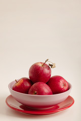 Red and green apples on a plate on a white background.