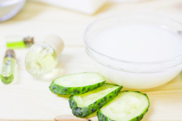 Cucumber home spa and hair care concept. Sliced cucumber, bottles of oil, sea salt, bathroom towel. White board background