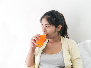 Asian pregnant woman drinking a glass of orange juice, lifestyle concept.