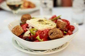 greek salad on plate and feta cheese on top.