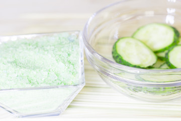 Cucumber home spa and hair care concept. Sliced cucumber, bottles of oil, sea salt, bathroom towel. Straw light background