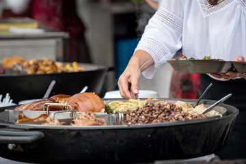 Latvian national cuisine. A woman puts hot dishes from a large pan.