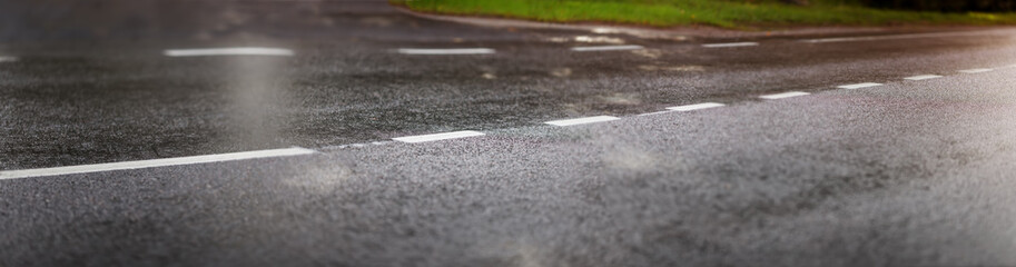 wet black asphalt road and white dividing lines