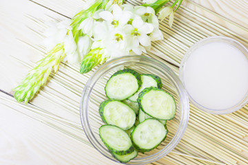 Cucumber home spa and hair care concept. Sliced cucumber, bottles of oil, bathroom towel. Straw light background