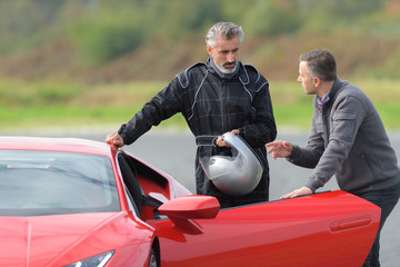 2 men on a race track talking near a ferrari