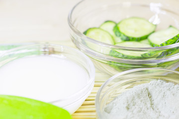 Cucumber home spa and hair care concept. Sliced cucumber, bottles of oil, bathroom towel. Straw light background