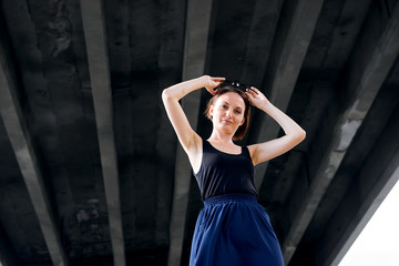 Fototapeta na wymiar young girl posing under the bridge, dressed in black, modern architecture