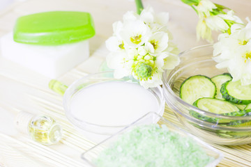 Obraz na płótnie Canvas Cucumber home spa and hair care concept. Sliced cucumber, bottles of oil, sea salt, bathroom towel. Straw light background
